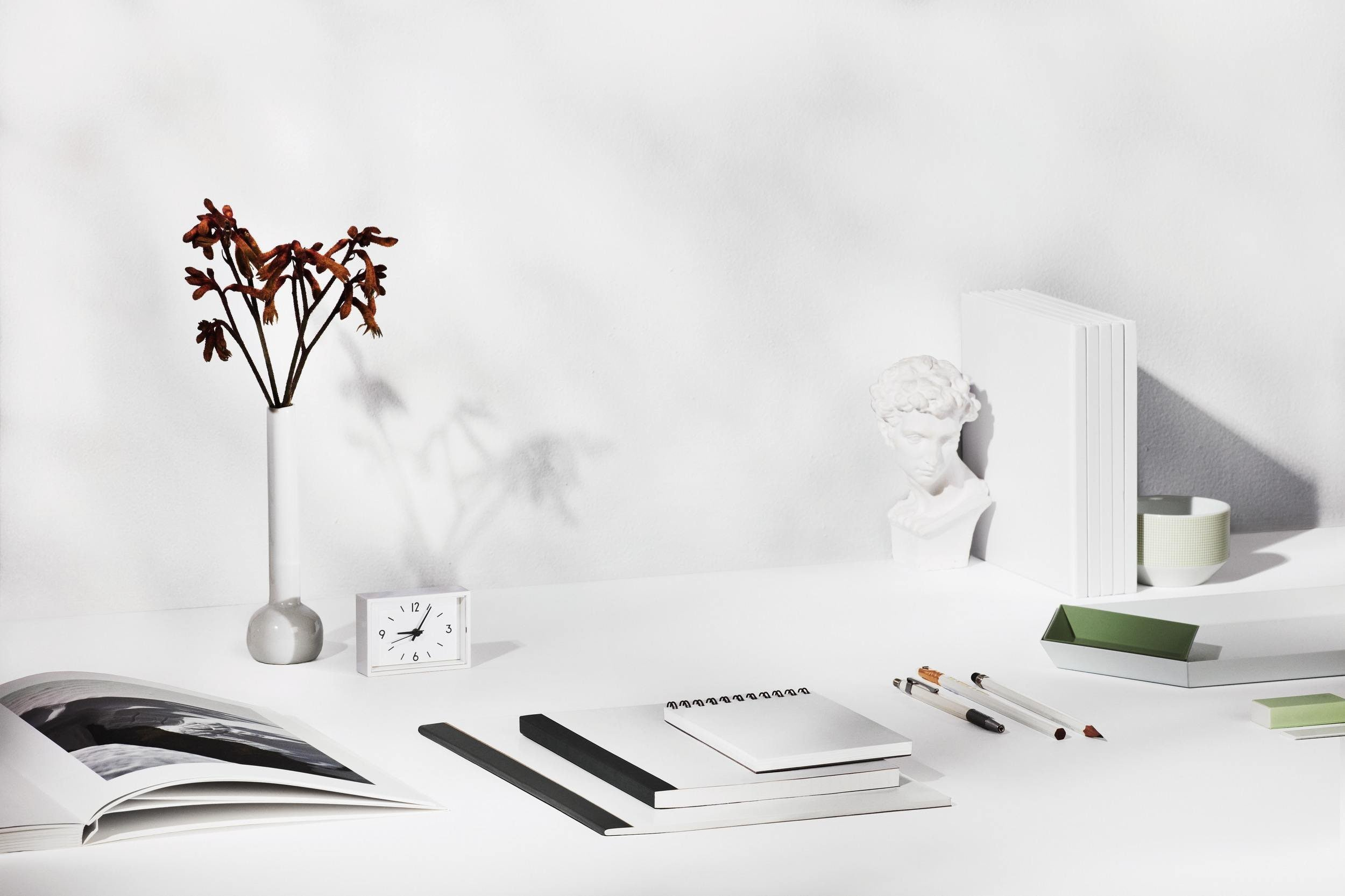 Minimal white desk with books, stationery and decorative objects